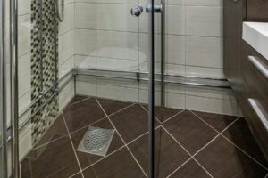 Pömpel auf Badezimmerboden neben Dusche